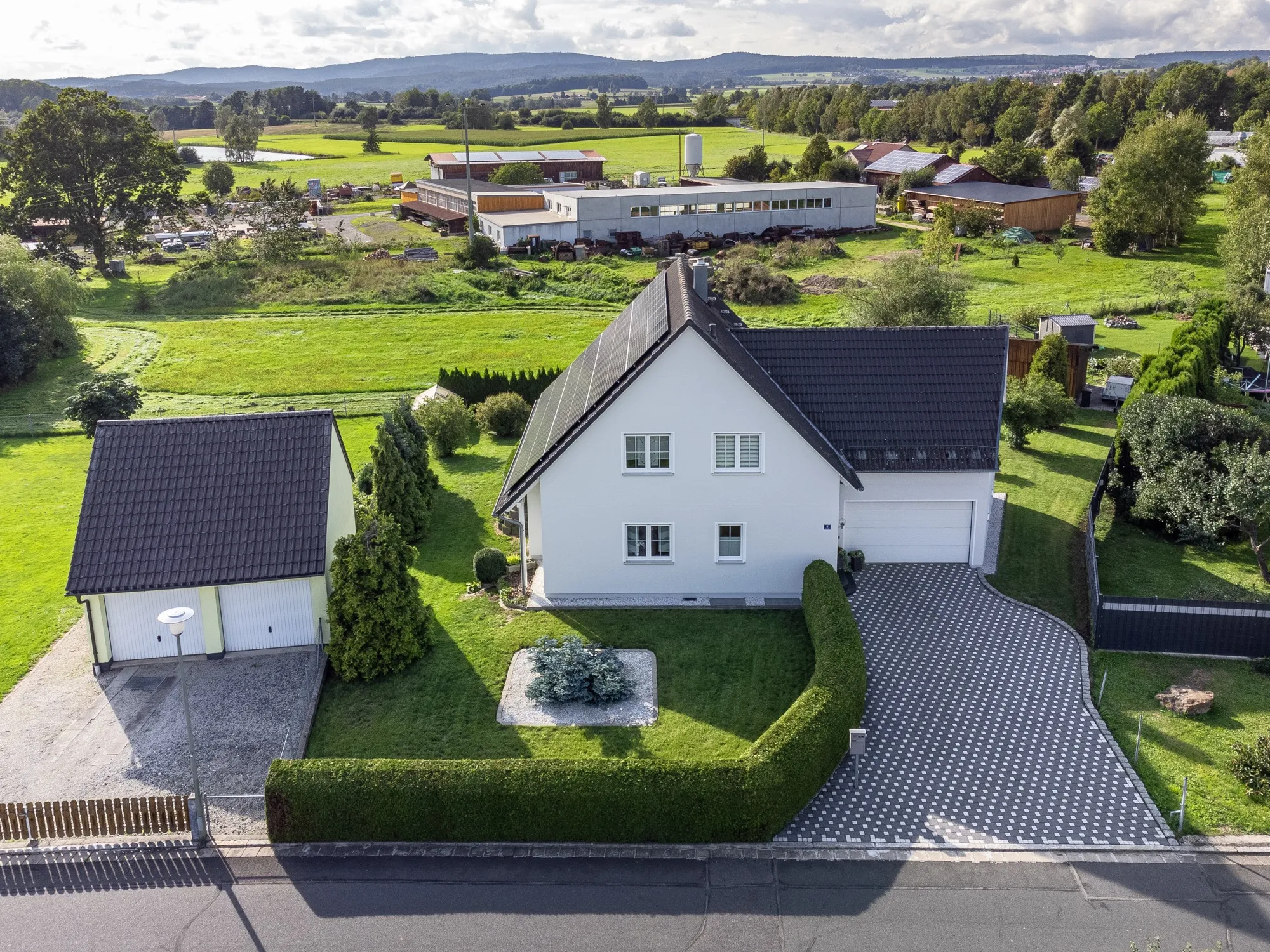 Luftaufnahme, die Haus, Zufahrt und Umgebung im Zusammenhang zeigt